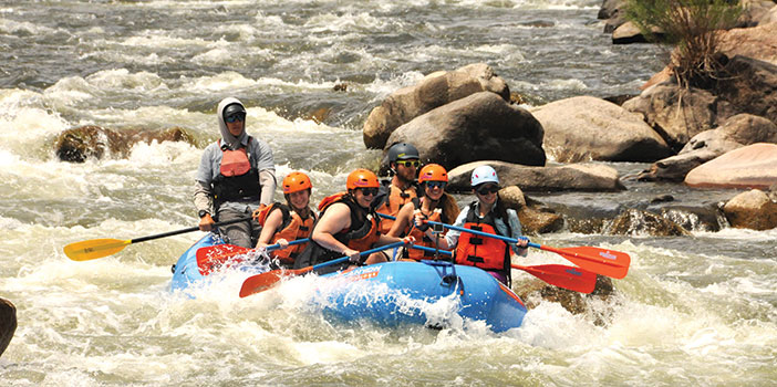group in raft paddling through rapids on Arkansas River