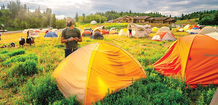 Man standing by a bunch of tents in a field