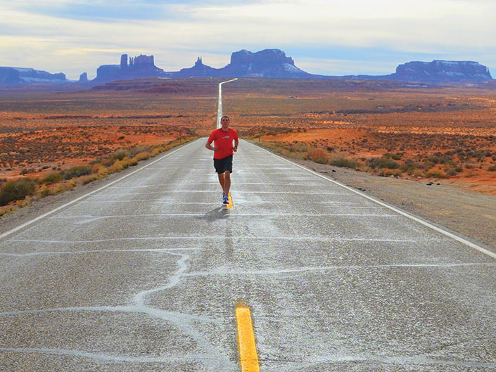 Cory Reese running on a desert road in monument valley