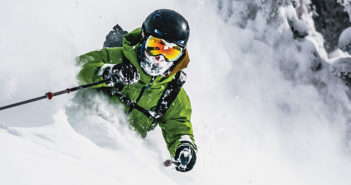 Skier in powder with green jacket and wearing a helmet