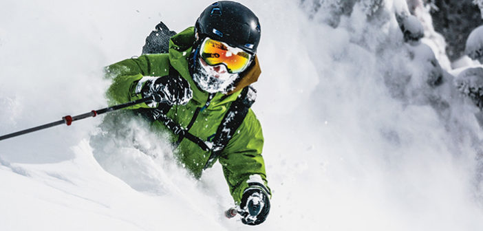 Skier in powder with green jacket and wearing a helmet