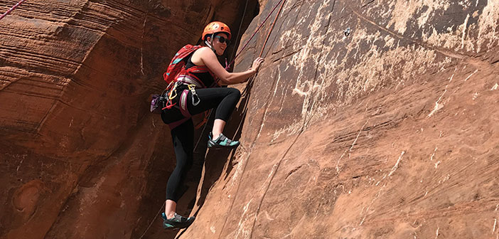 Woman rock climbing on a red rock cliff