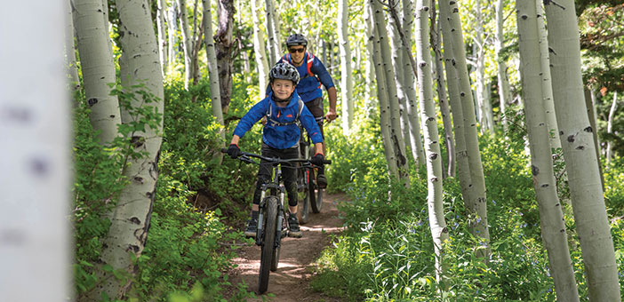 Man and child mountain biking on a forest trail