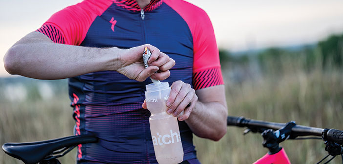 cyclist pouring Meal Replacements into water bottle