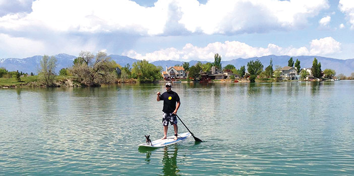man with his dog on a stand up paddle board on Stansbury lake
