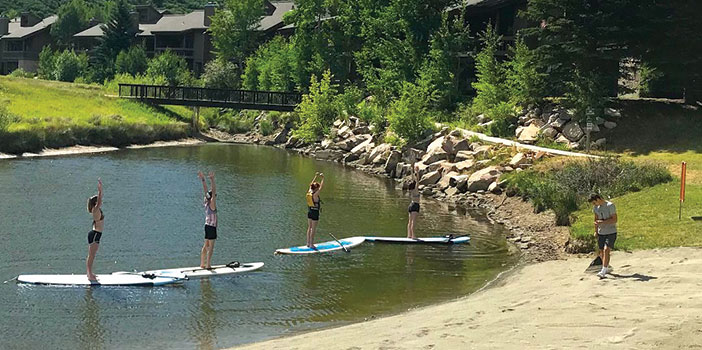 group doing yoga on stand up paddleboards on Deer Valley Pebble beach in park city