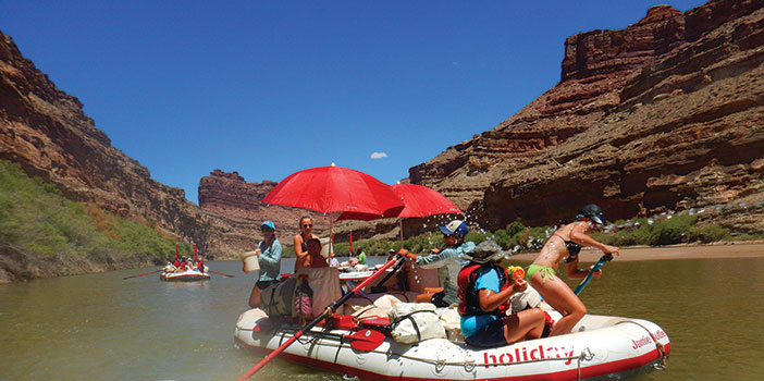 group having a water fight on a raft being rowed on Cataract Canyon